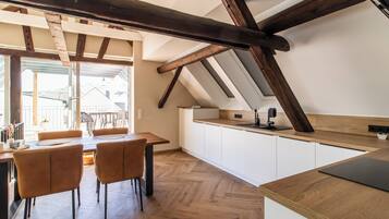 Eine moderne Küche mit Holzbalken, weißen Schränken und einem Essbereich mit Stühlen.