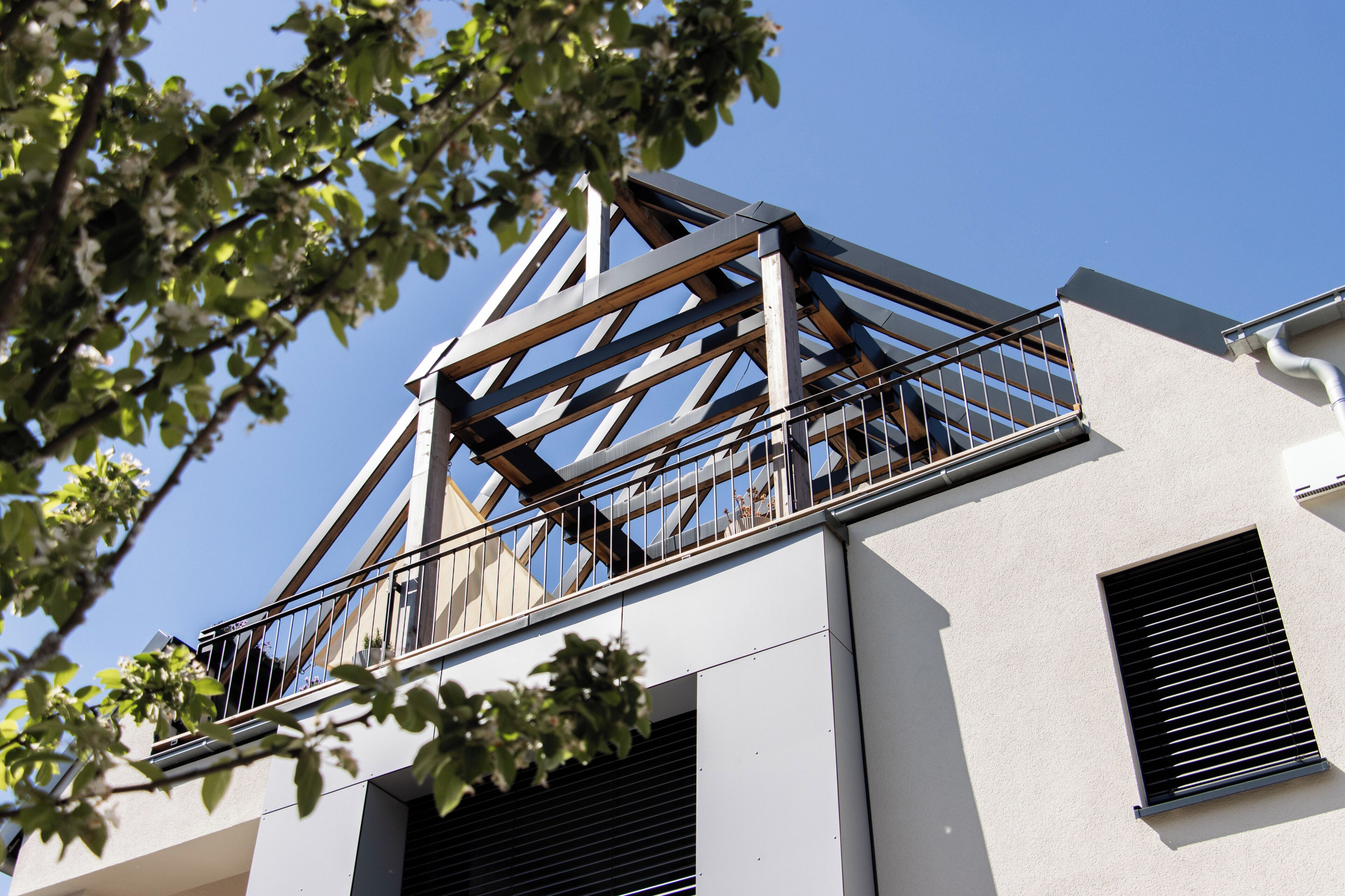 Ein modernes Gebäude mit Balkon, großen Fenstern und blauem Himmel.