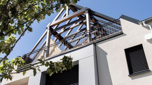Um edifício moderno com varanda, janelas amplas e céu claro.