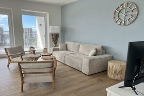 A modern living room with a sofa, armchair, and a television. - Holiday apartment with 3 bedrooms (Bremerhaven)