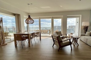 Ein geräumiges Wohnzimmer mit Essbereich, großen Fenstern und Blick auf die Stadt.