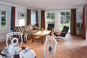 A living room with a sofa, chairs, a table, and a TV. - Rose House in Heide Park (Nebel\/Süddorf)