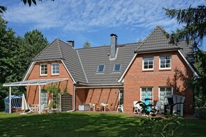 A two-story house with a covered patio, brick exterior, and a sloped roof. - Rose House in Heide Park (Nebel\/Süddorf)