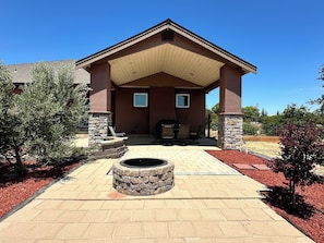 A house with a covered patio, stone pillars, a fire pit, and outdoor furniture.