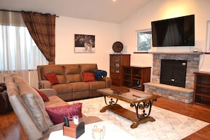 A living room with a sofa, a coffee table, a fireplace, and a television.