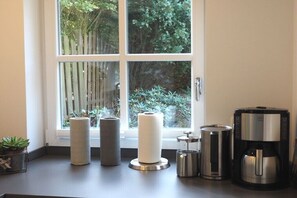 A kitchen counter with a coffee maker, paper towel holders, and a potted plant.