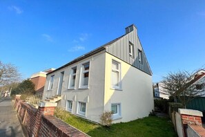 Ein modernes, zweistöckiges Haus mit geneigtem Dach, einer Ziegelwand und einem kleinen Vorgarten.