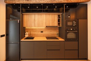 Een moderne keuken met een inbouwoven, een koelkast en houten kastjes.
