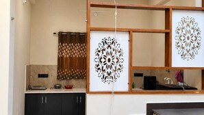 A modern kitchen with dark cabinets, a countertop, and a ceiling fan. - Shivansh Stays (Ujjain)