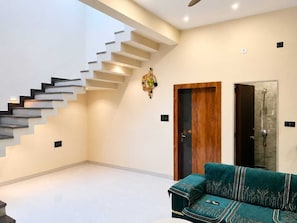 Un interior moderno con una escalera, una puerta de madera y un sofá verde.