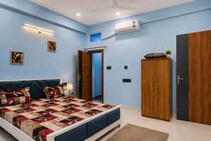 A bedroom with a bed, wardrobe, and an air conditioning unit.