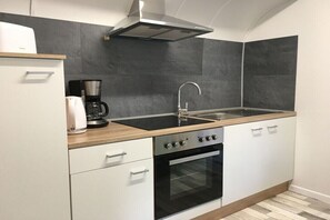 A compact kitchen with a stove, oven, sink, and a coffee maker. - Rittershof - Circus Booth (Seelwig)