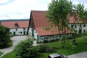 Il s’agit d’un bâtiment traditionnel à colombages, doté d’un toit recouvert de tuiles rouges, d’une allée pavée et d’une voiture garée devant.