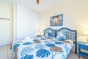 Ein Schlafzimmer mit einem Bett, einem Nachttisch, einer Wandlampe und einer Tür.