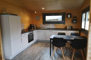 Eine kompakte Küche mit Kühlschrank, Herd, Spüle sowie ein Essbereich mit Tisch und Stühlen.