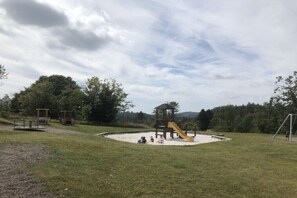 Ein Spielplatz mit Rutsche, Klettergerüsten und einem umzäunten Spielbereich.