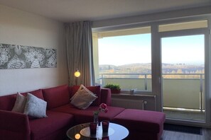 Ein rotes Sofa mit Blick auf eine Stadtlandschaft durch ein großes Fenster.