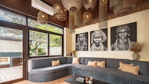 A modern living room with a grey sectional sofa, a black coffee table, and woven pendant lights. - Villa Frika Canggu (Canggu)