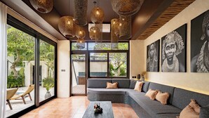 A modern interior with a large window, a gray sofa, a coffee table, and decorative wall art. - Villa Frika Canggu (Canggu)