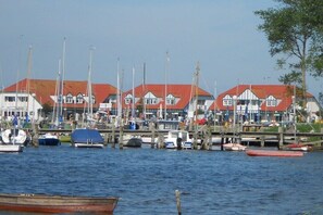 Ein Ufergrundstück mit mehreren vor Anker liegenden Booten, einer Anlegestelle und einer Reihe von Gebäuden mit roten Dächern.