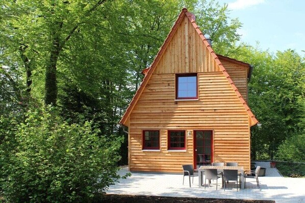 Eine Holzhütte mit Satteldach, kleinem Fenster und einer Tür.