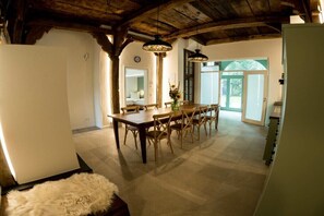 Ein Essbereich mit Holztisch und -stühlen, einer Kristallleuchtre und Blick ins Freie.