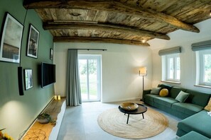 Ein Wohnzimmer mit Holzboden, einem grünen Sofa, einem runden Teppich und einem flachbildschirmfernseher an der Wand.