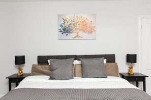 Una camera d'albergo con un letto, due comodini, un quadro appeso al muro e una porta.