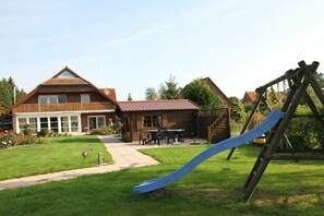 A residential area with a house, a slide, and a swing set. - Holiday apartment with 1 bedroom (Esens\/Moorweg-Wagnersfehn)