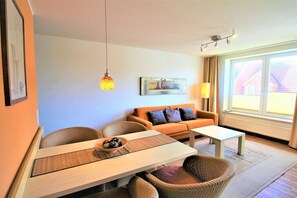 Ein Wohnzimmer mit einer Couch, Sesseln, einem Couchtisch und einem Bild an der Wand.