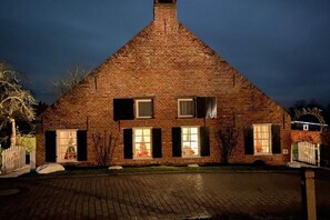 Ein Haus aus Backsteinen mit einem Giebeldach, einem Schornstein und einem gepflasterten Auffahrt.