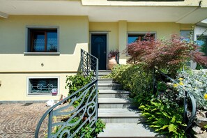 A residential building with a staircase leading to a door, surrounded by greenery and a metal railing. - 'Nido in Città' Room with Mountain View, Private Garden and Air Conditioning (Udine)