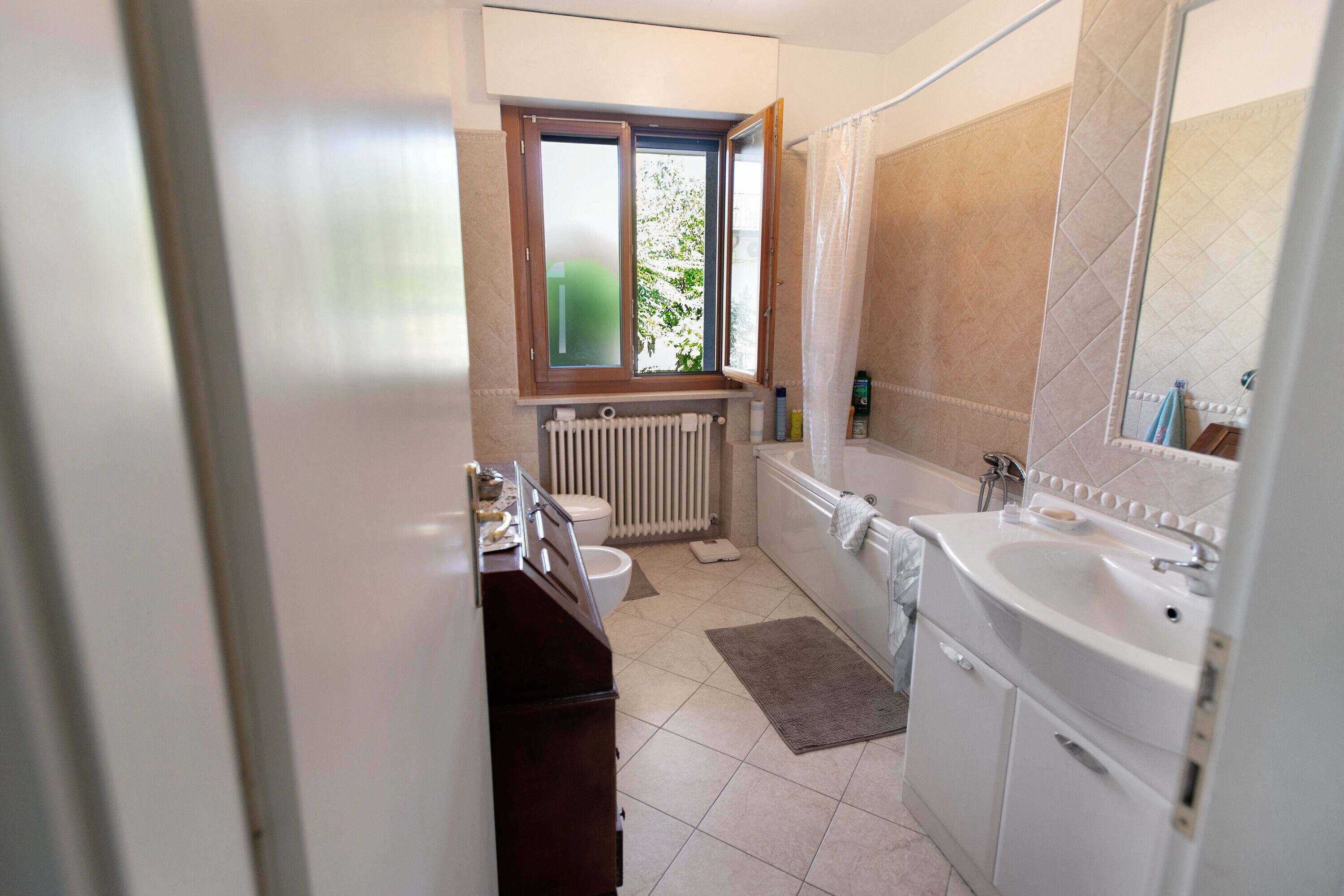 Un baño con ventana, bañera, lavabo e inodoro.