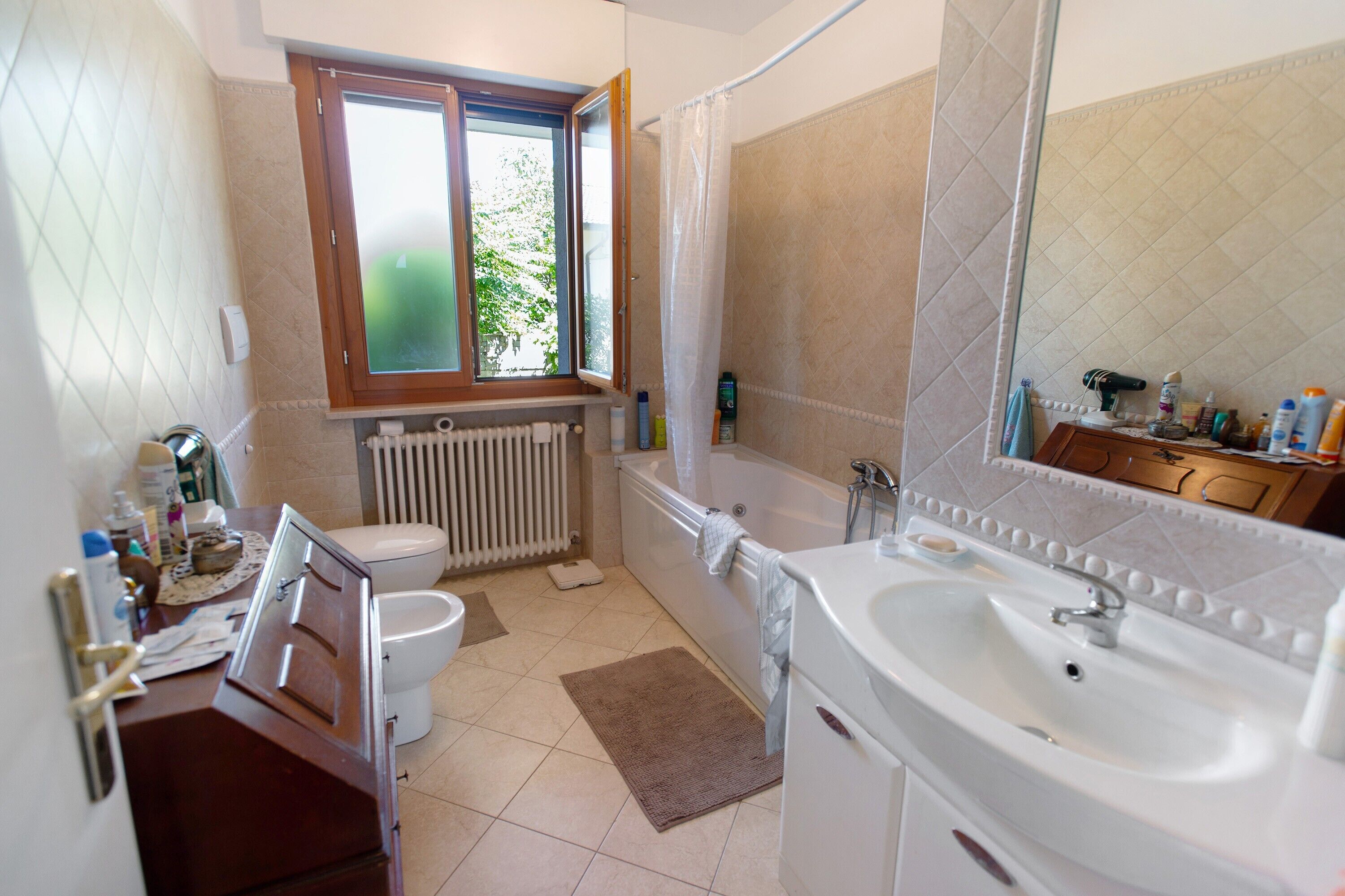 A bathroom with a toilet, bathtub, sink, and a window.