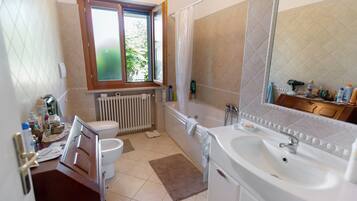 A bathroom with a toilet, bathtub, sink, and a window.