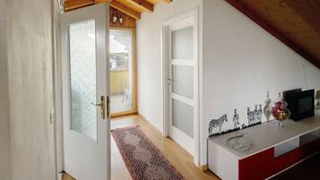 A hallway with a wooden ceiling, a white door, a red cabinet, and a small table with decorative items.
