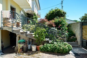 A courtyard with a metal staircase, potted plants, and a stone wall. - 'Nido in Città' Room with Mountain View, Private Garden and Air Conditioning (Udine)