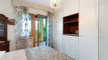 A bedroom with a bed, a dresser, a wardrobe, and a window with curtains.