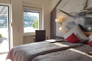 Ein Schlafzimmer mit einem Bett, einem Sessel, einem Fenster und einer Wandlampe.