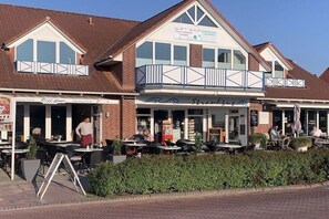 Ein Gebäude mit Balkon, Außenbereich zum Sitzen und Hinweisen auf ein Restaurant.