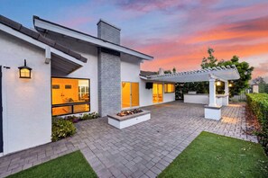 Una casa moderna con un patio, una chimenea y una pérgola.