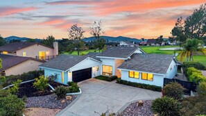 A residential area with houses, a driveway, and a golf course in the background.