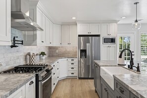 Una cocina moderna con armarios blancos, electrodomésticos de acero inoxidable y encimera de mármol.