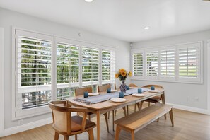 A dining room with a long table, chairs, and a vase of flowers.