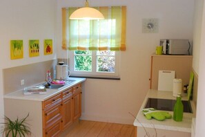 Eine kleine Küche mit Fenster, Spüle, Mikrowelle und einer Arbeitsplatte.