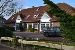 Ein Wohnhaus mit Auto auf der Auffahrt, einem Holzzaun und einem kleinen Teich.