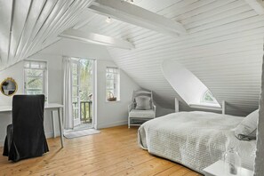 A bedroom with a sloped ceiling, a bed, a chair, a desk, and a window. - Country farmhouse close to the beach (Hals)