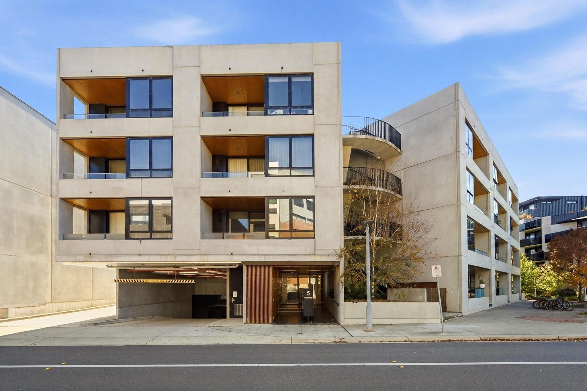 A multi-story building with a flat facade, large windows, and a parking garage entrance.