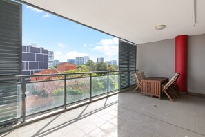 A balcony with a city view, a red pillar, and a table with chairs. - Modern 2-Bed Apartment Near Airport (Wolli Creek)