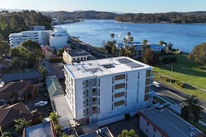 A multi-story hotel with a flat roof, located near a body of water with boats. - Coastal 3-Bed Retreat Near Batemans Bay (Batemans Bay)